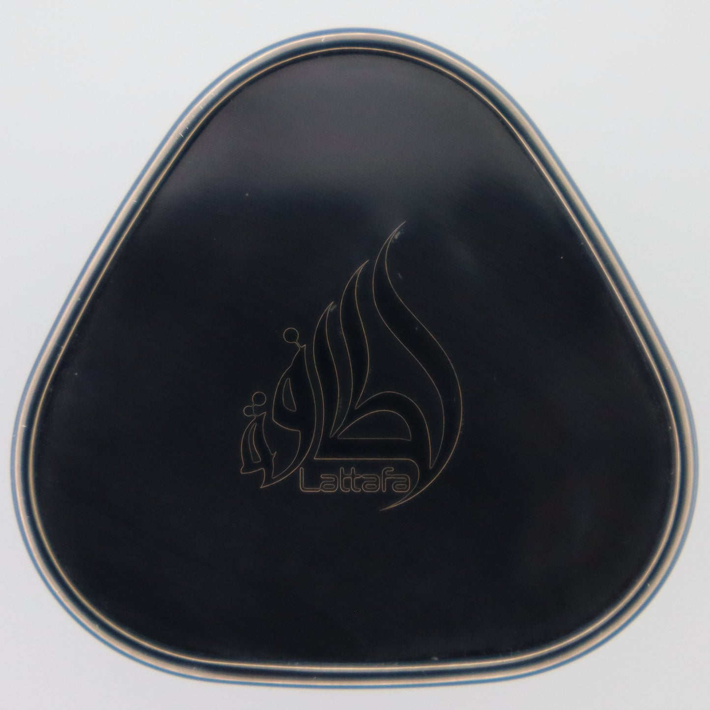 A black triangular compact perfume cap with a silver metallic border and an engraved Lattafa logo in the center, set against a plain white background.