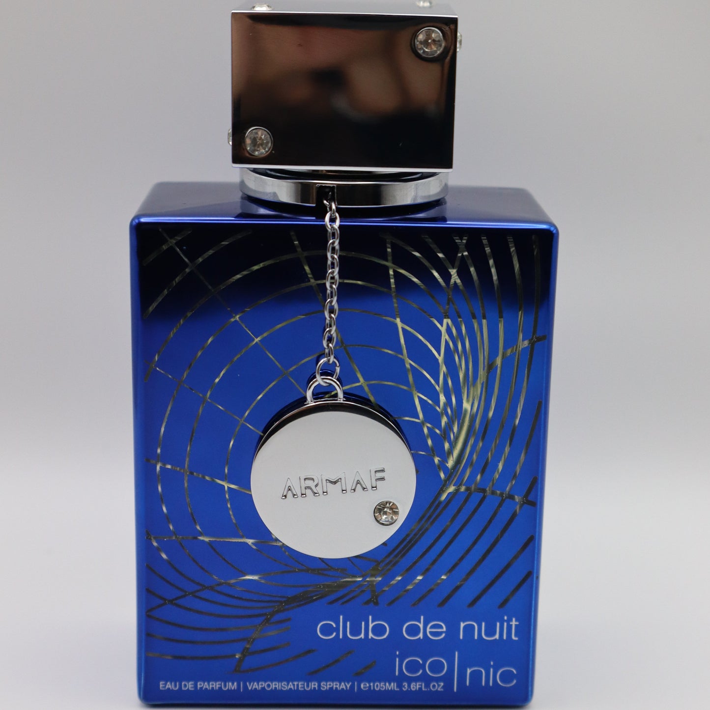 Blue perfume bottle with a circular tag bearing the embossed brand name 'ARMAF'. The bottle has details including 'club de nuit' and 'ico|nic'.