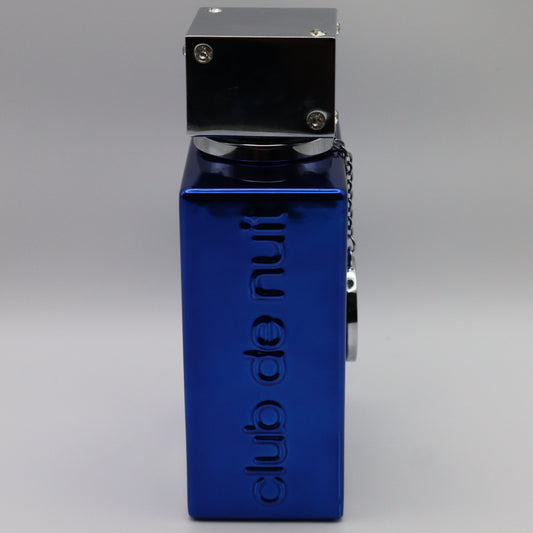 A blue metal perrfume bottle with a silver top, featuring the vertical text 'club de nuit' embossed. The bottle is shown from a side profile view on a neutral gray background.