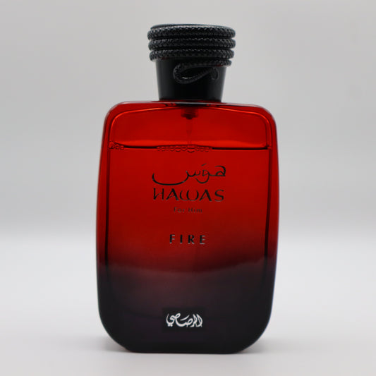 Glass bottle of perfume, transitioning in color from red to black at the bottom. It's labeled 'HAWAS For Him' and 'FIRE' and has a black cap.