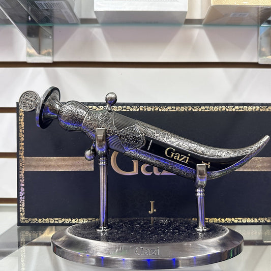 J. Junaid Jamshed Gazi dagger-shaped bottle on its stand in front of the box, photographed at the Sheikh Scents shop